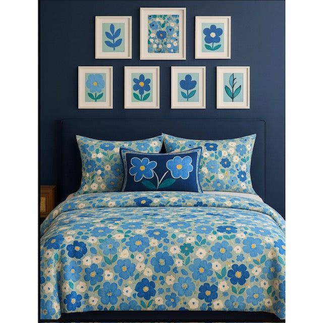Floral bedding set with matching pillows against a blue wall with framed artwork. Joan Davis Art Studios